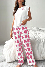 Woman wearing a pink Heart Print Pants Lounge Set on a bed.