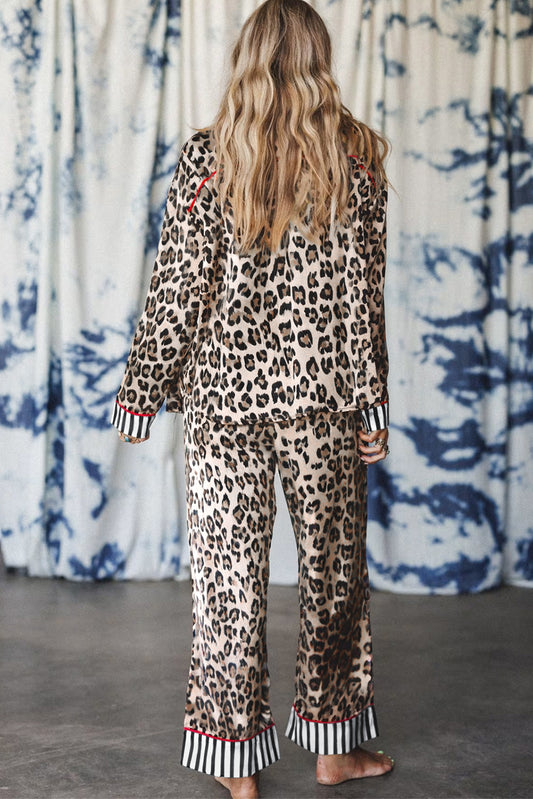 Person wearing a leopard print outfit with striped cuffs and hem in front of a patterned curtain.
