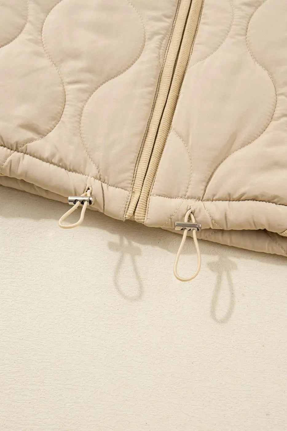 Bottom hem of Quilted Fleece‑Lined Winter Gilet in khaki showing adjustable drawstrings and double zipper design.