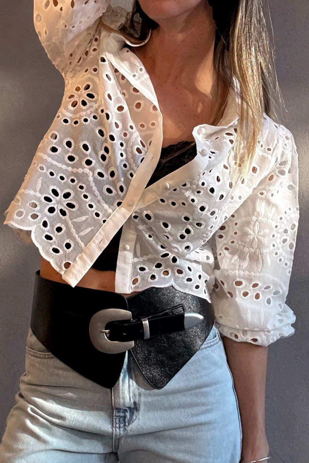 Person wearing a White Cutwork Embroidered Crop Top with a black belt and light blue jeans against a neutral background
