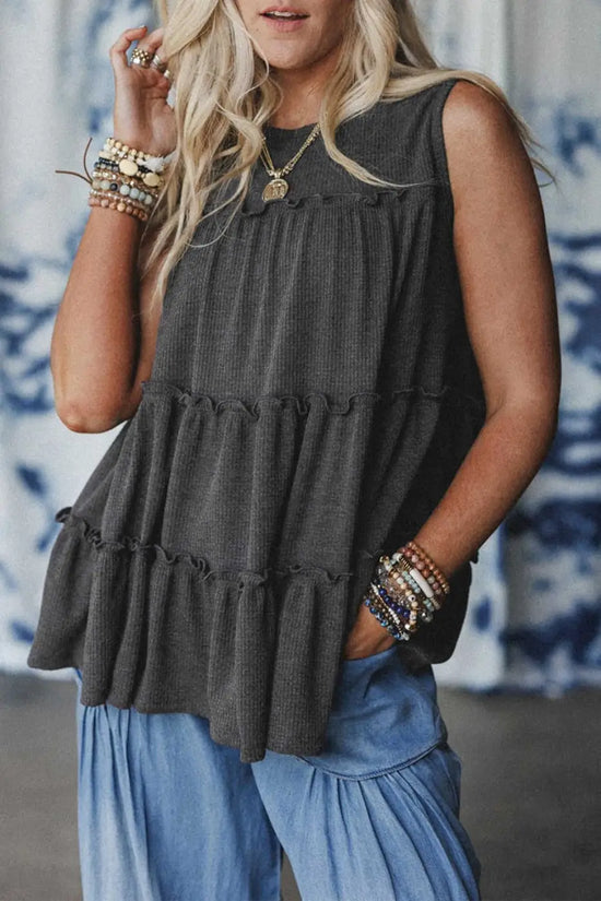 Dark grey tiered frill tank top for women styled with light blue pants, featuring a relaxed A-line fit and textured fabric.