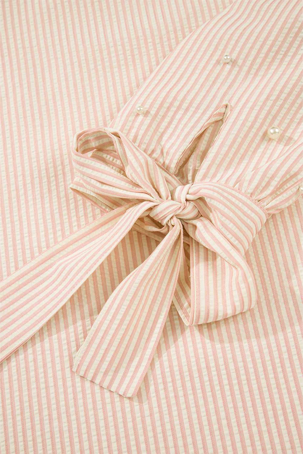 Detail of the bow cuff on the Bow Cuff Pearl Embellished Blouse, highlighting feminine striped fabric and tied sleeve design.