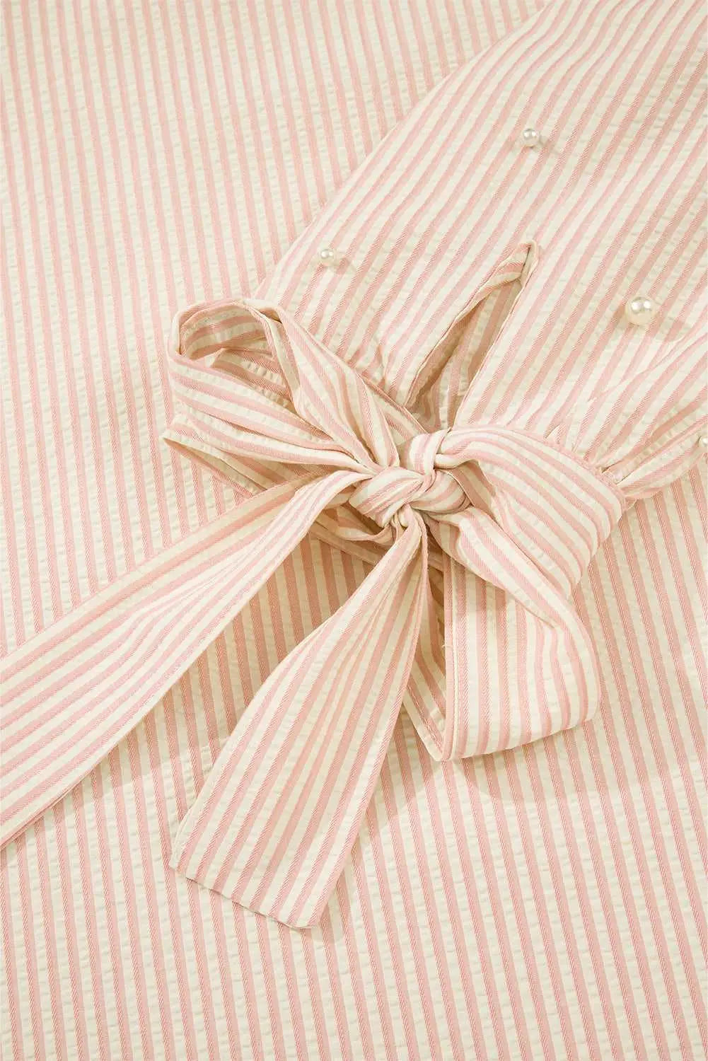 Detail of the bow cuff on the Bow Cuff Pearl Embellished Blouse, highlighting feminine striped fabric and tied sleeve design.