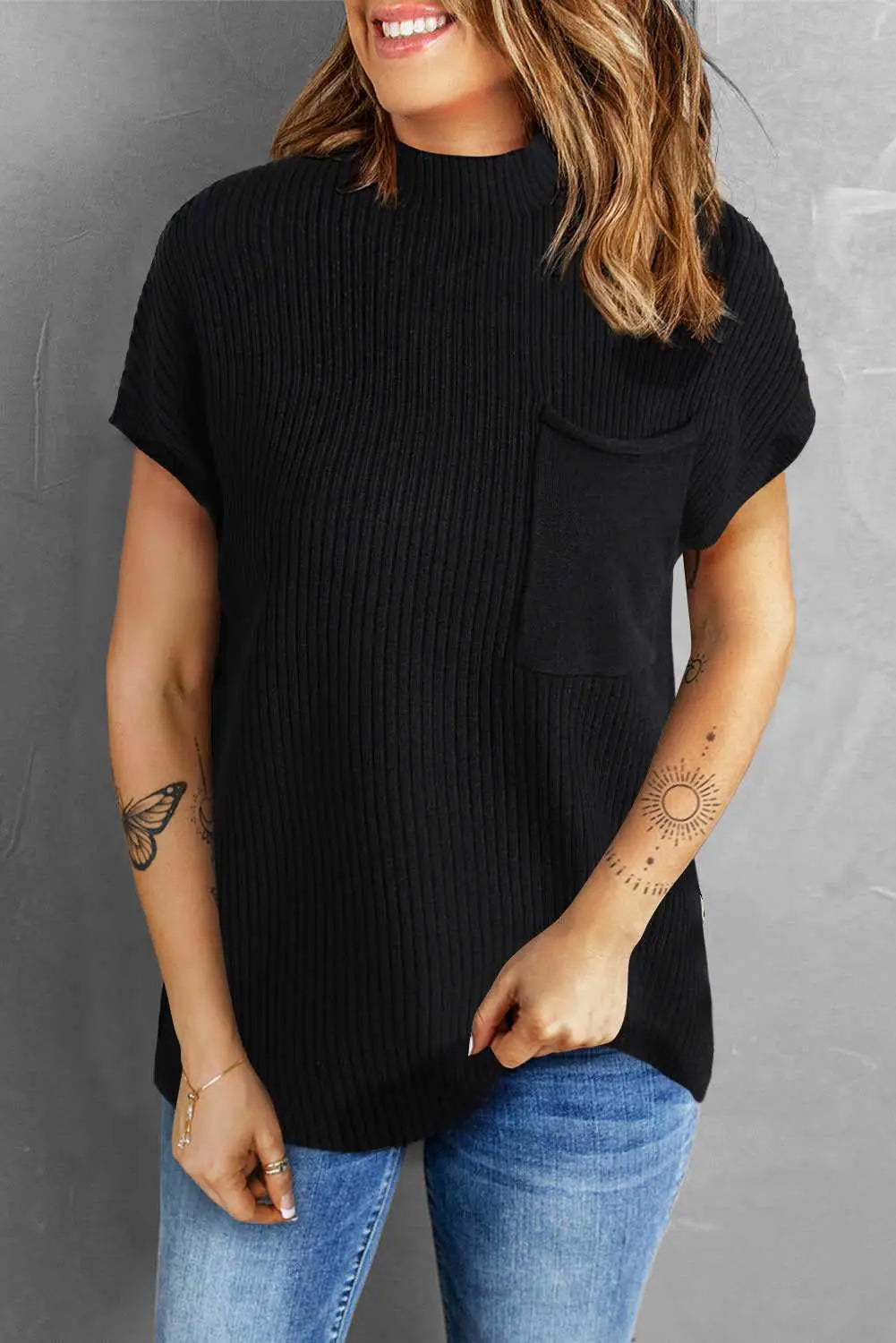 Woman in black ribbed knit short sleeve sweater with chest pocket, styled with blue jeans for a cozy and casual daily outfit.