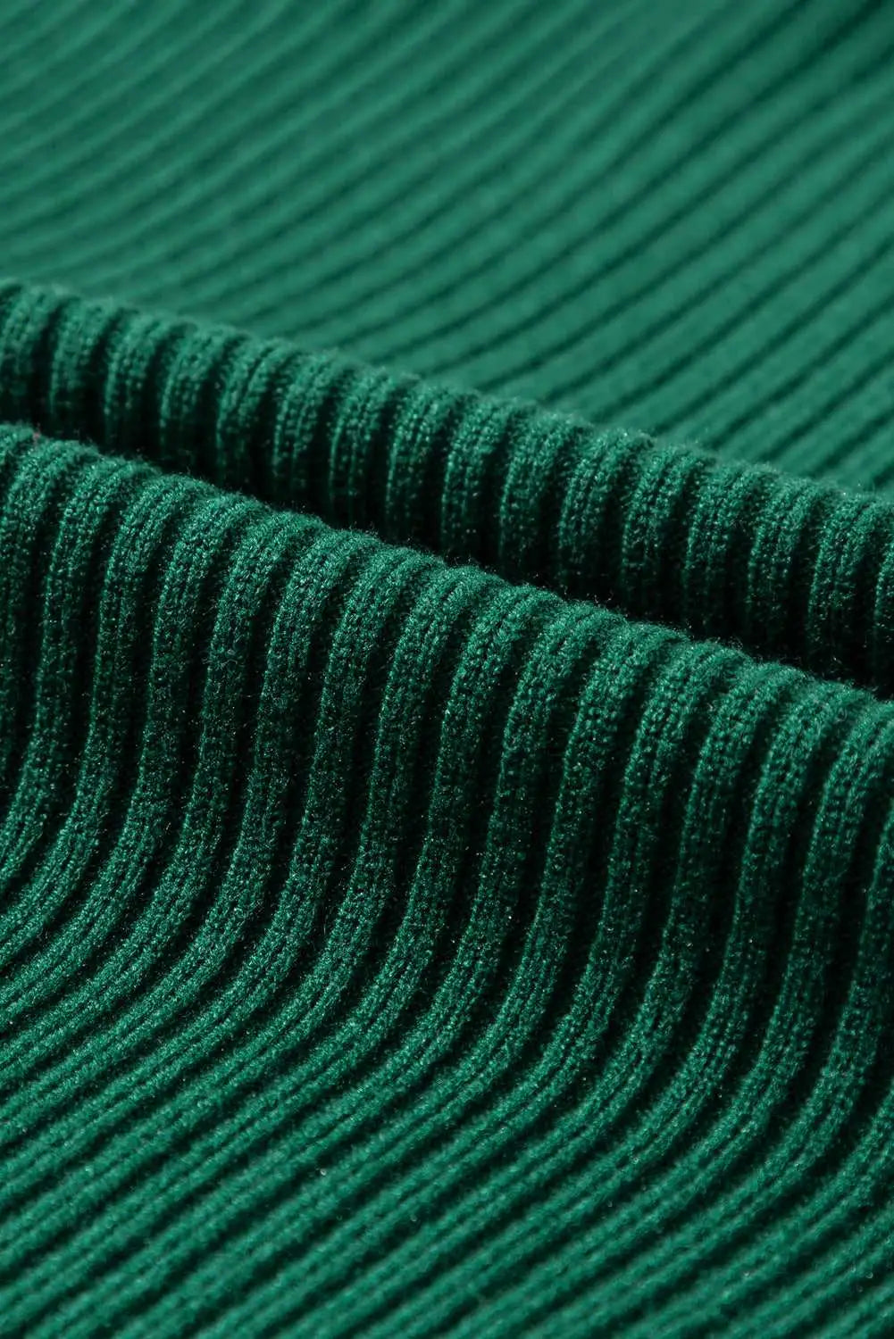 Detailed view of green ribbed knit fabric texture from the short sleeve sweater, highlighting its soft and cozy material.