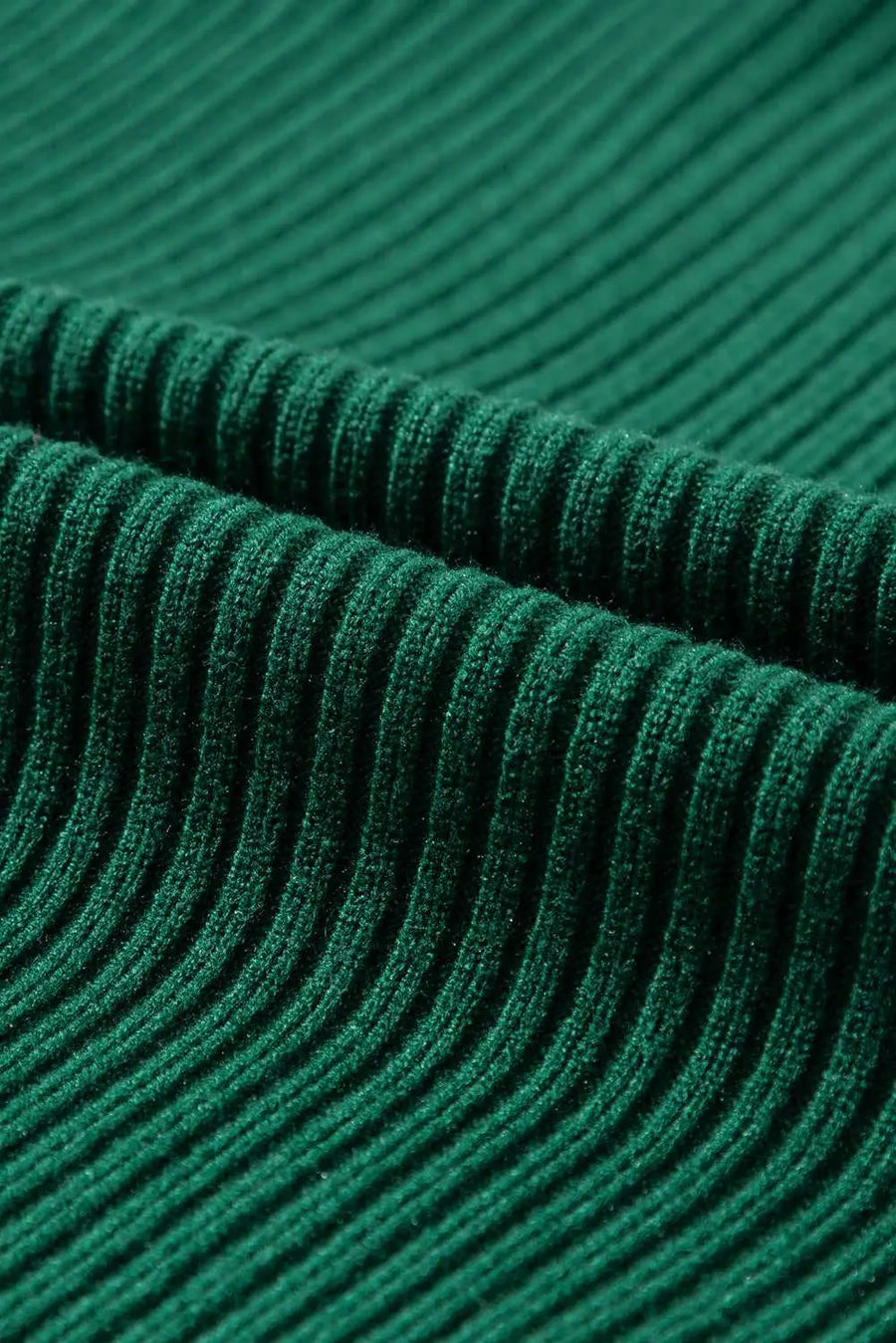 Detailed view of green ribbed knit fabric texture from the short sleeve sweater, highlighting its soft and cozy material.