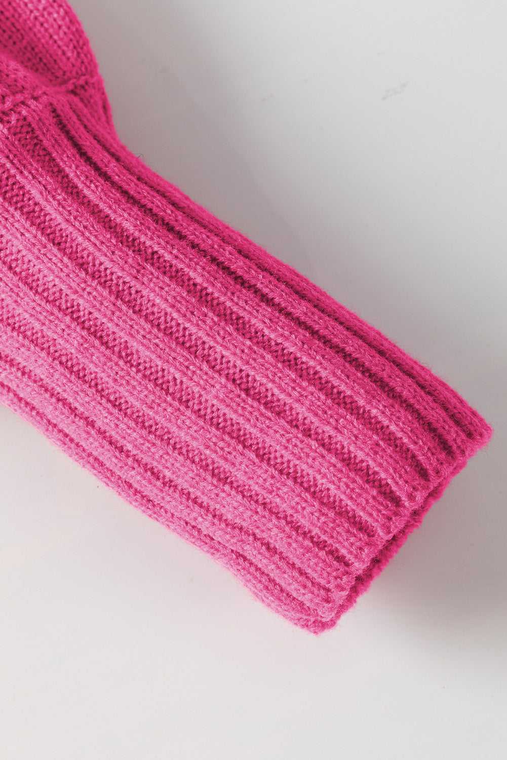 Close-up of ribbed sleeve on pink high neck sweater, showing detailed knit texture for a cozy winter fit.