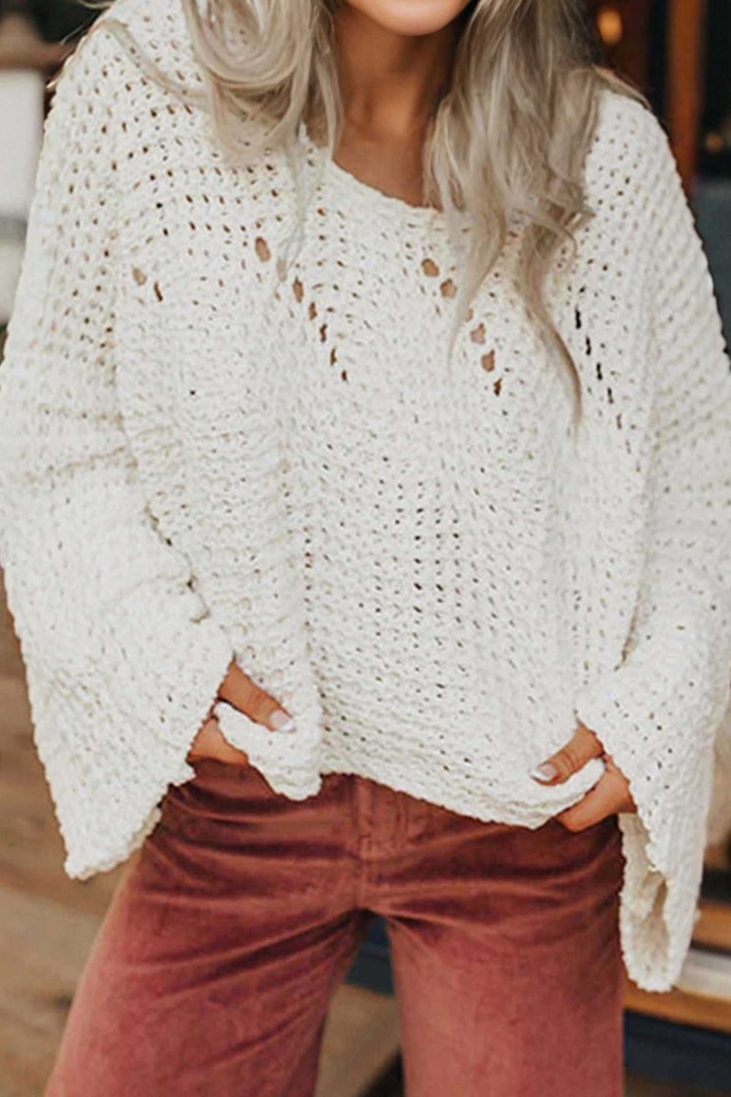 White wide sleeve hollow knit jumper with open-knit texture, styled casually with rust-colored pants for a cozy fall look.
