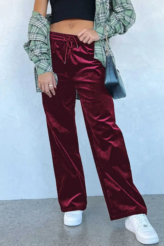 Burgundy velvet drawstring trousers paired with plaid shirt and crossbody bag, showcasing cozy winter style in wide-leg silhouette.