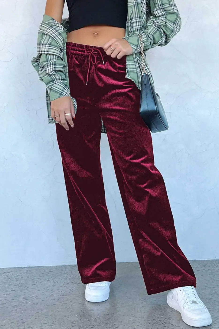 Burgundy velvet drawstring trousers paired with plaid shirt and crossbody bag, showcasing cozy winter style in wide-leg silhouette.