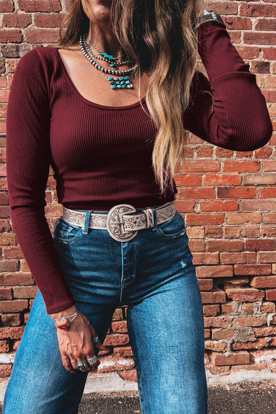 Women's brown ribbed long sleeve crop top in soft knit fabric, styled with turquoise jewelry and western belt for a trendy autumn outfit.