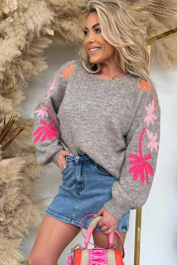 Grey Floral Embroidered Sleeve Jumper for women styled with a denim skirt, showcasing bold pink and orange floral knit on sleeves.