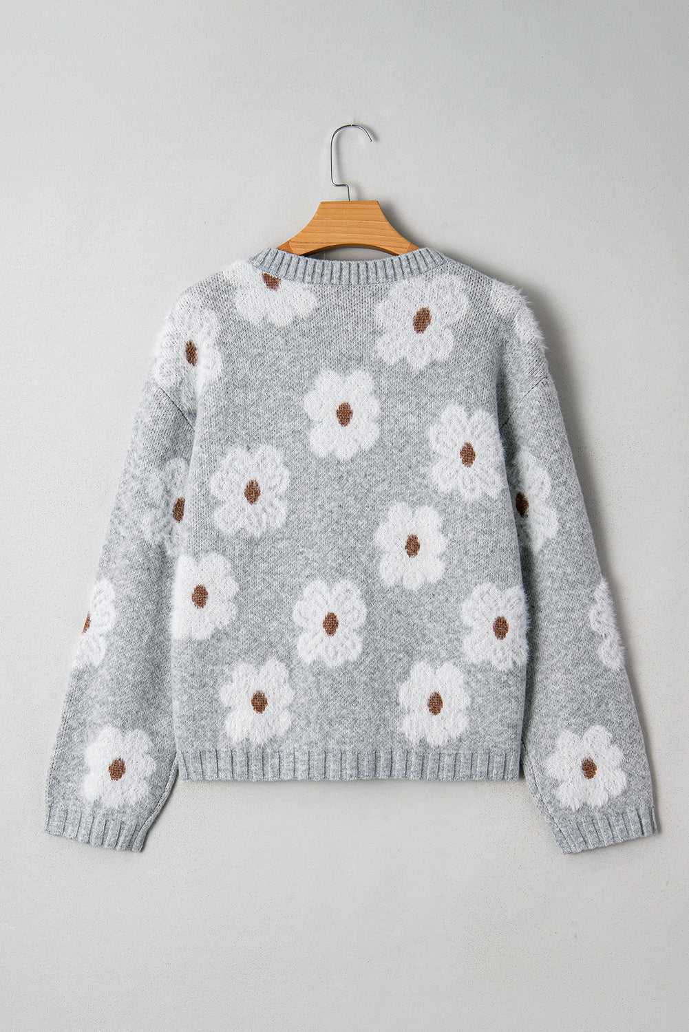 Back view of FashionFitz Oversized Grey Floral Knit Jumper – V‑Neck showcasing all-over white floral knit design on soft grey fabric.