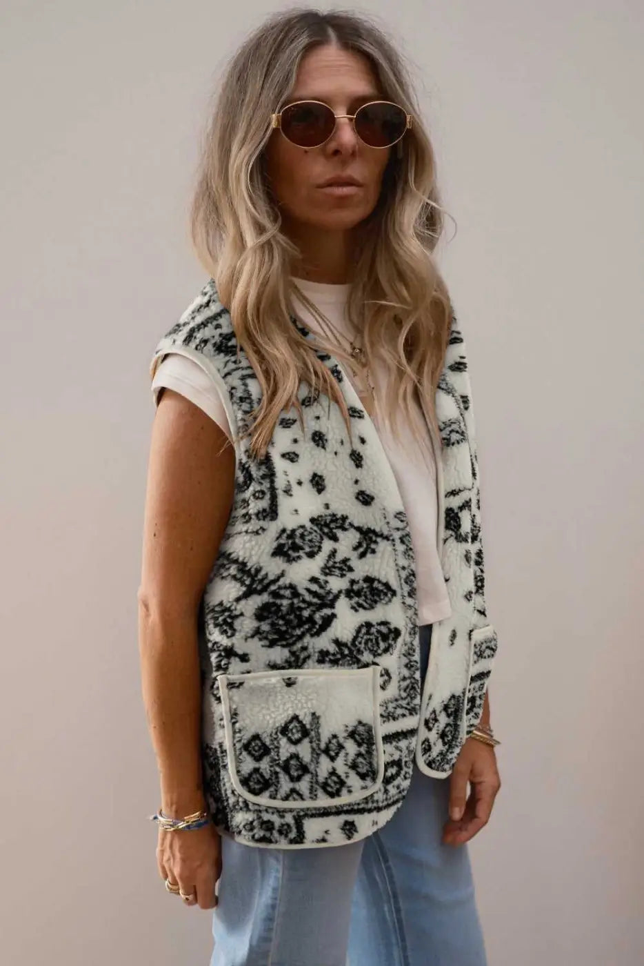 Model styling the beige paisley sherpa vest with sunglasses and casual wear, highlighting the Western-inspired outerwear look.