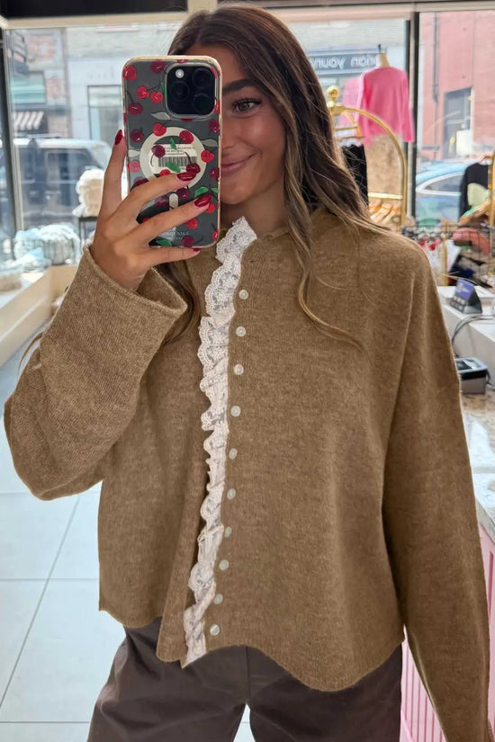 Soft taupe cardigan with white lace trim and button-down front, perfect for layering in cooler seasons. Elegant and comfortable knitwear.