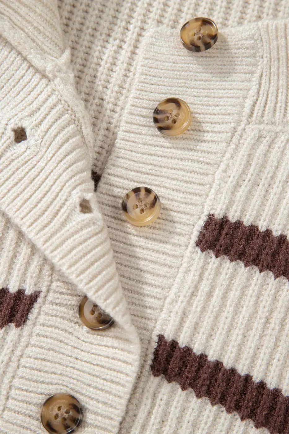 Detail of button placket and ribbed knit texture on casual slouchy striped Henley jumper in cream and brown.