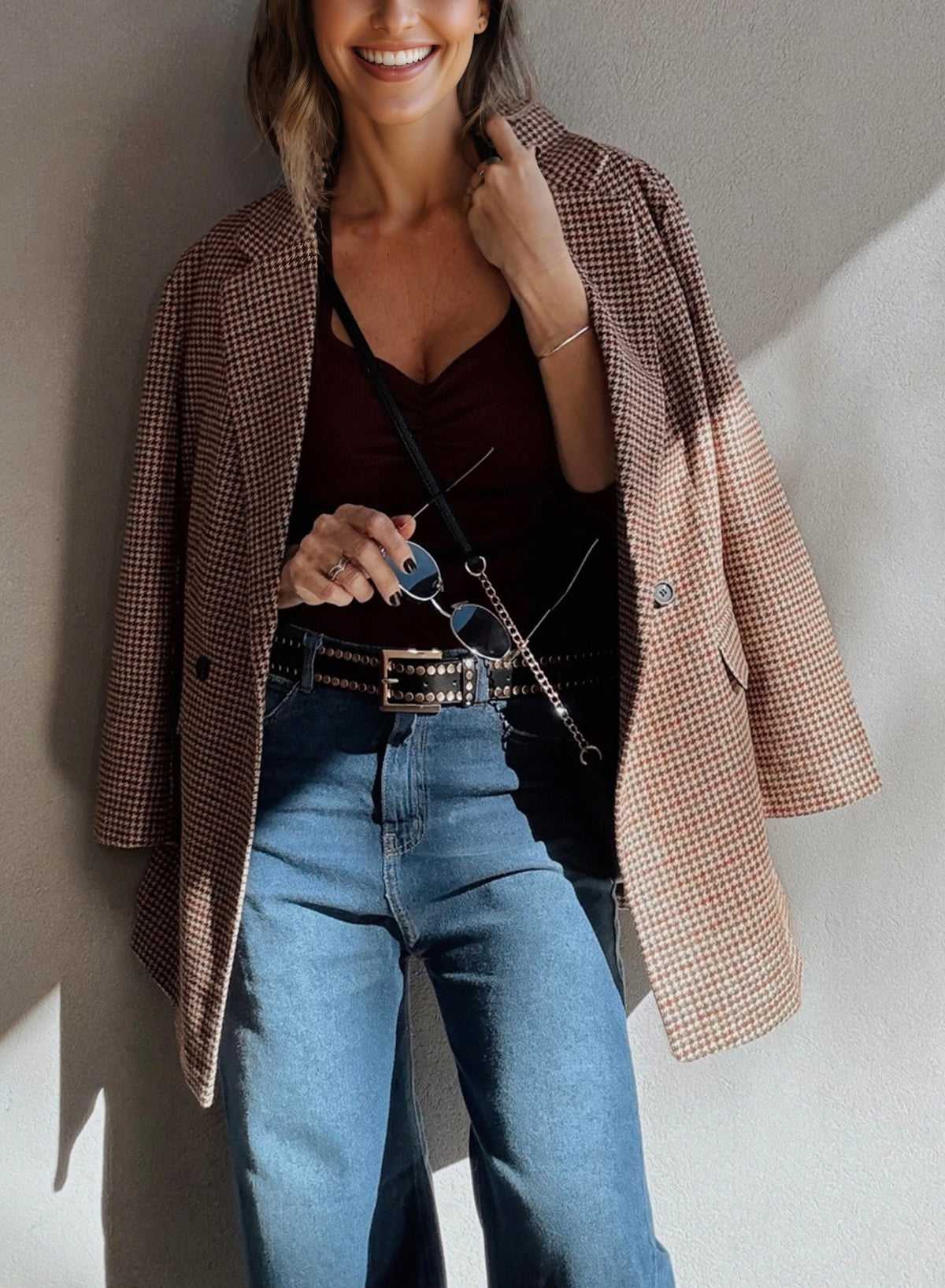 Ladies Brown Houndstooth Fitted Blazer draped over shoulders with a burgundy top and studded belt, styled for a chic fall ensemble.