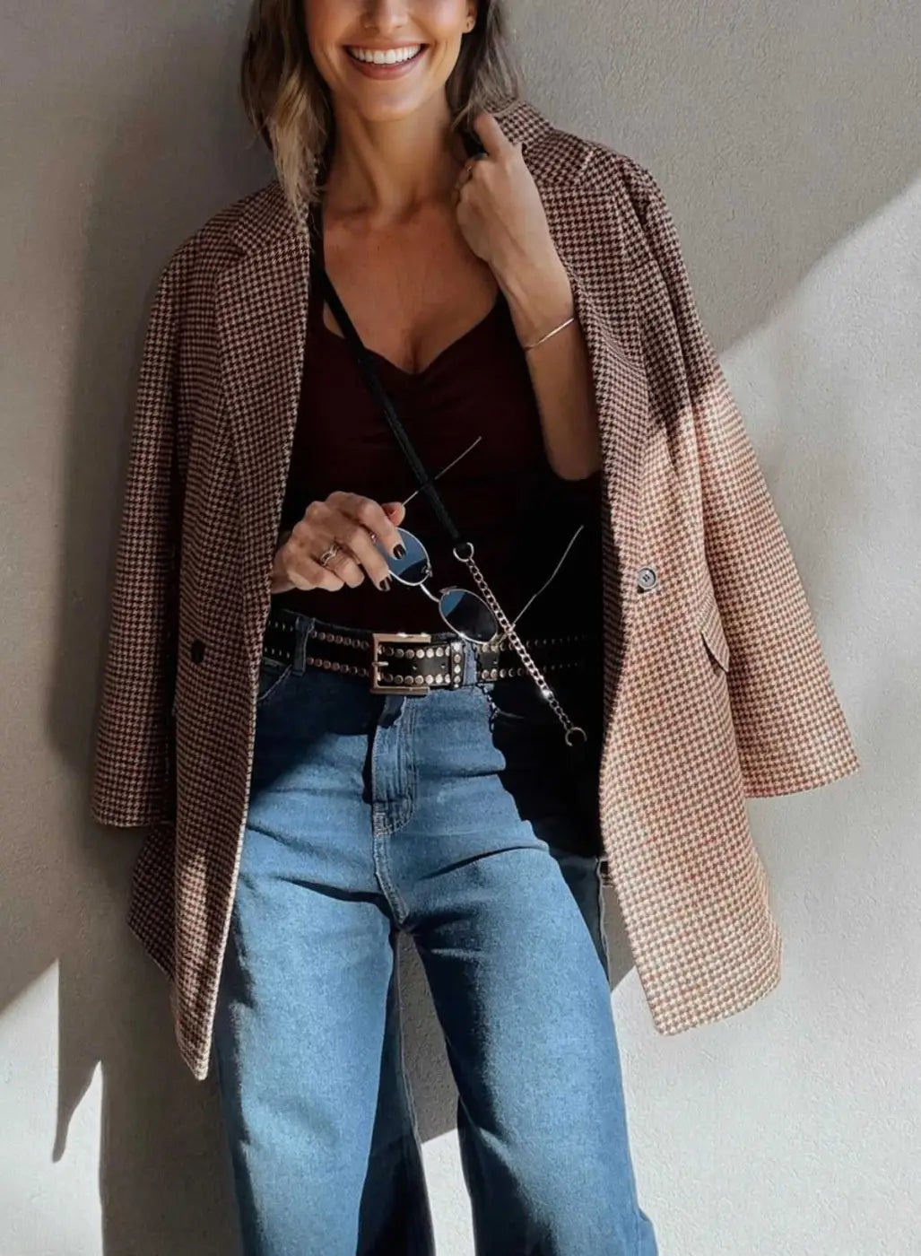 Ladies Brown Houndstooth Fitted Blazer draped over shoulders with a burgundy top and studded belt, styled for a chic fall ensemble.
