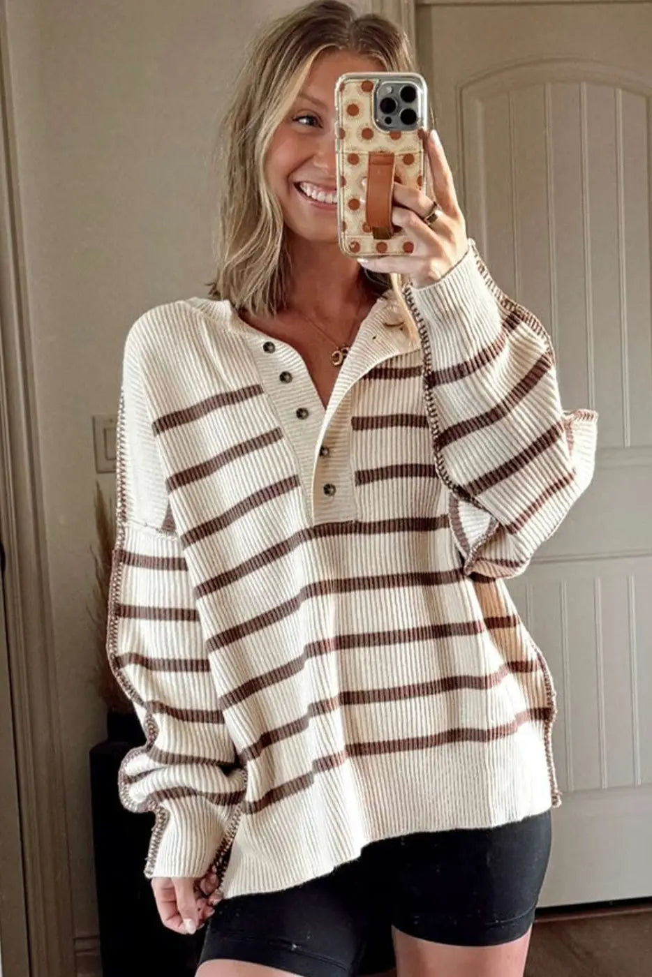 Casual slouchy striped Henley jumper styled with black biker shorts, featuring ribbed knit texture and brown stripes.