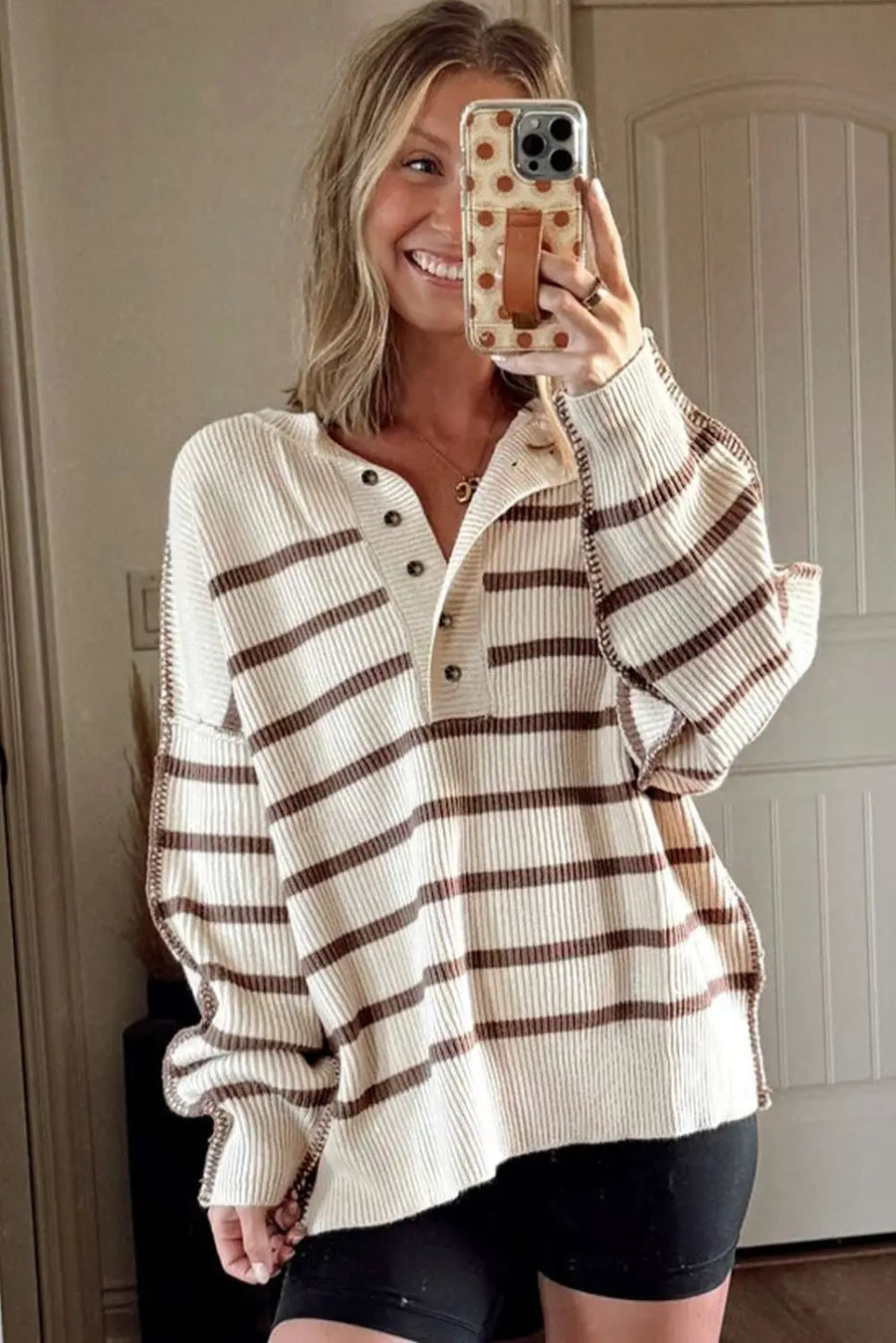 Casual slouchy striped Henley jumper styled with black biker shorts, featuring ribbed knit texture and brown stripes.