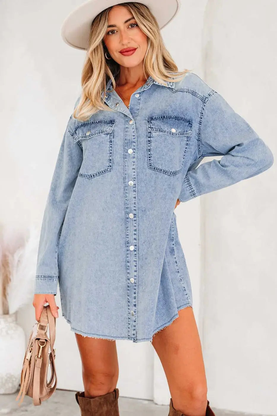 Light blue oversized denim dress women with raw hem and front buttons, styled casually with long sleeves and chest pockets for daily wear.