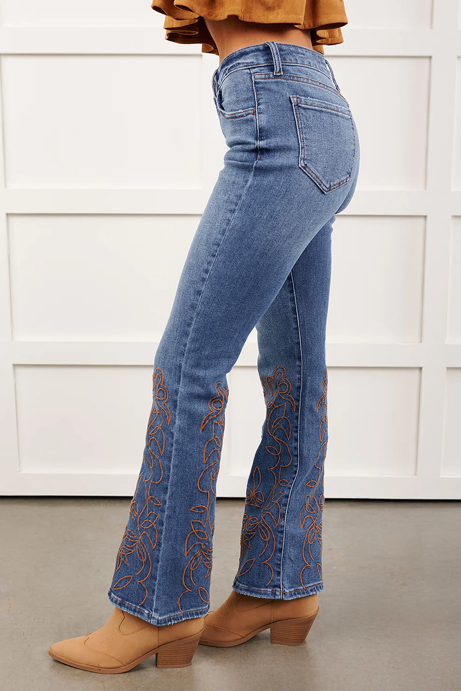 Embroidered flare leg jeans — styled with fitted white top and heeled boots