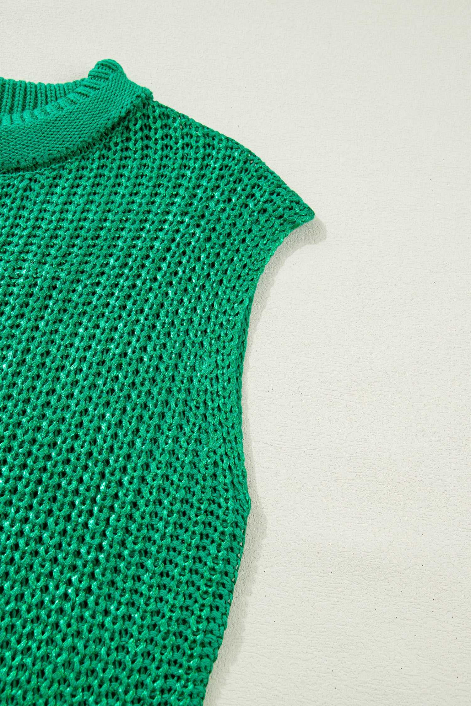 Sleeveless detail of green high neck knit top with airy acrylic weave. Lightweight summer sweater tee in a relaxed fit.