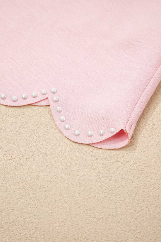 Close-up of a pink fabric with pearl embellishments on a beige background