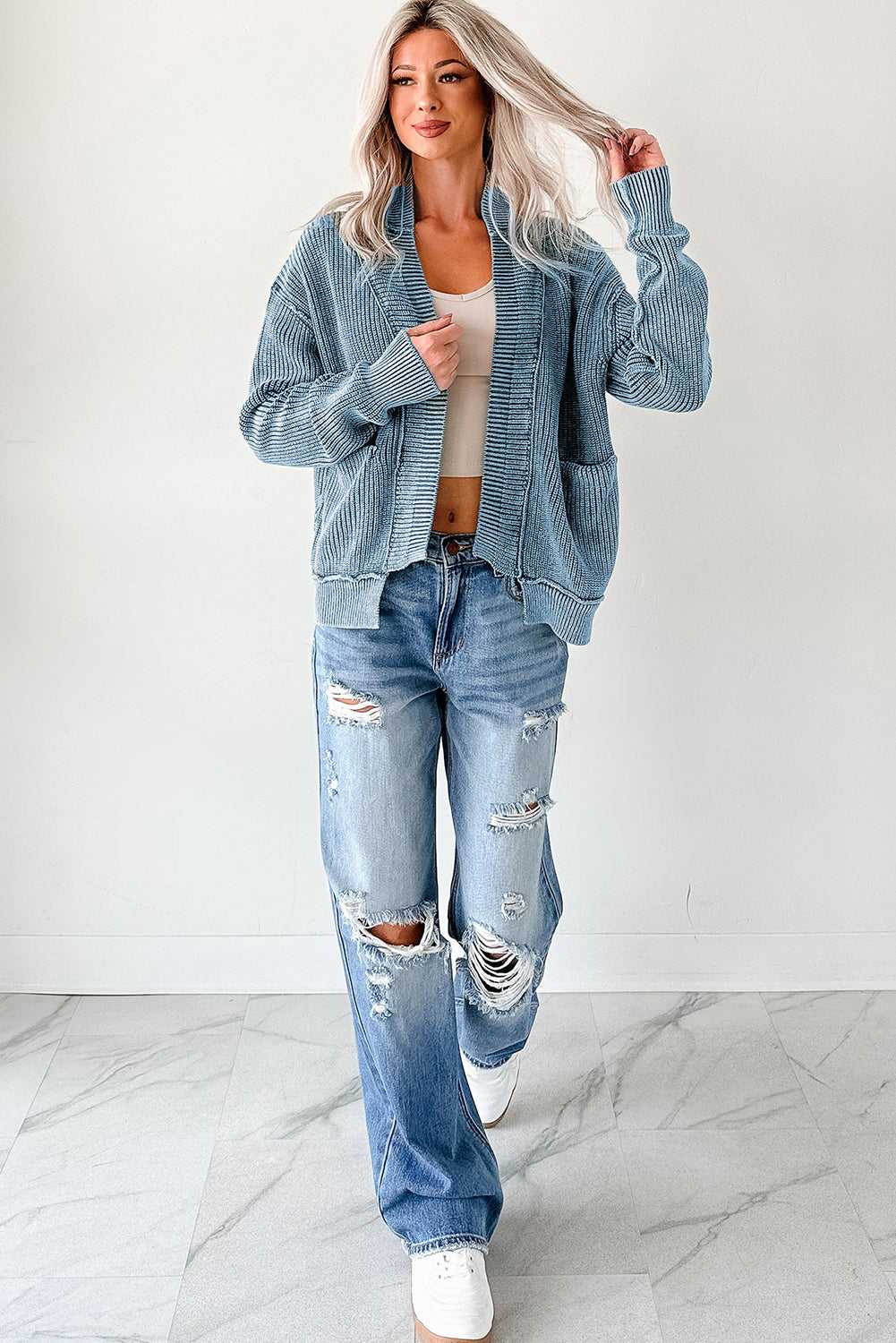 Full-body view of woman in blue stonewash patchwork knit open cardigan with distressed jeans and sneakers, styled for a laid-back fall outfit.