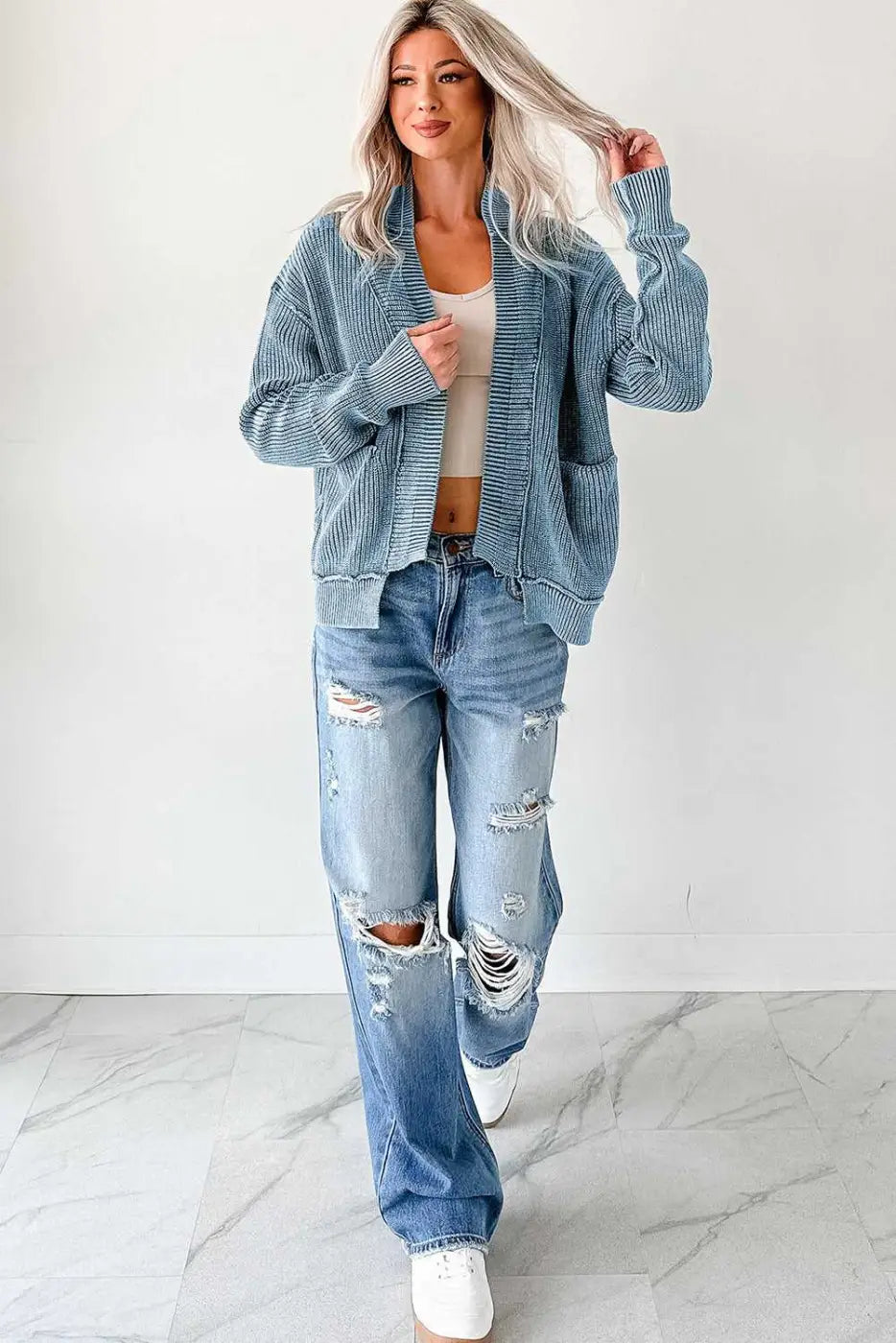 Full-body view of woman in blue stonewash knit open cardigan paired with ripped jeans and sneakers, styled for casual wear.