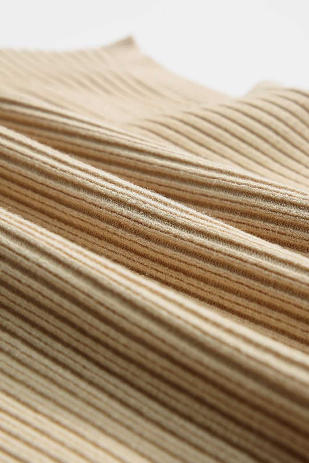 Macro shot of the ribbed knit fabric on the oatmeal sweater dress, highlighting its soft, cozy texture for winter wear.