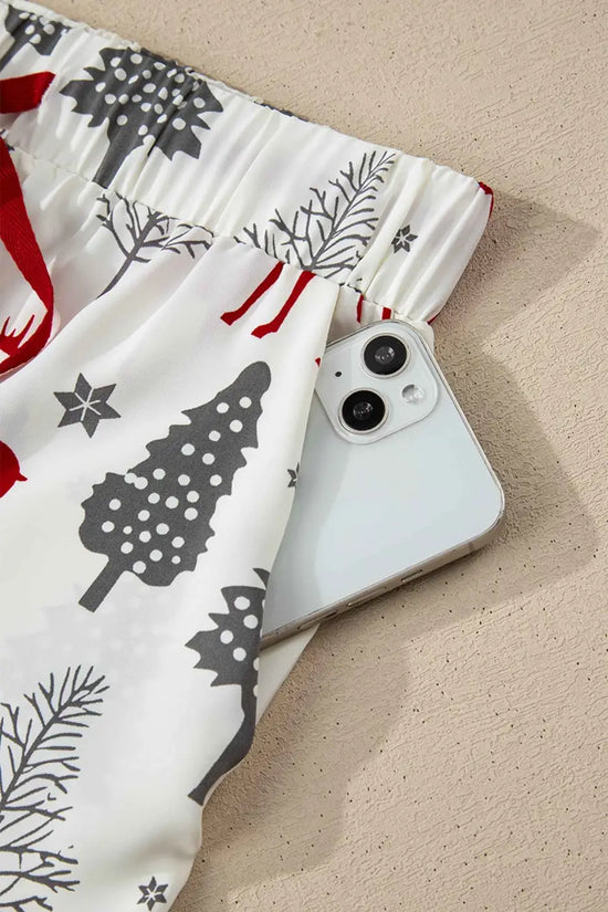 Elastic waistband shorts with pocket from White Christmas Print Velvet Trim Pyjamas, holding a phone for practical and cozy holiday wear.