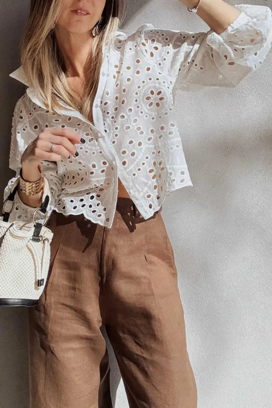 White Cutwork Embroidered Crop Top with puff sleeves paired with brown pants and a woven handbag for a modern spring look.