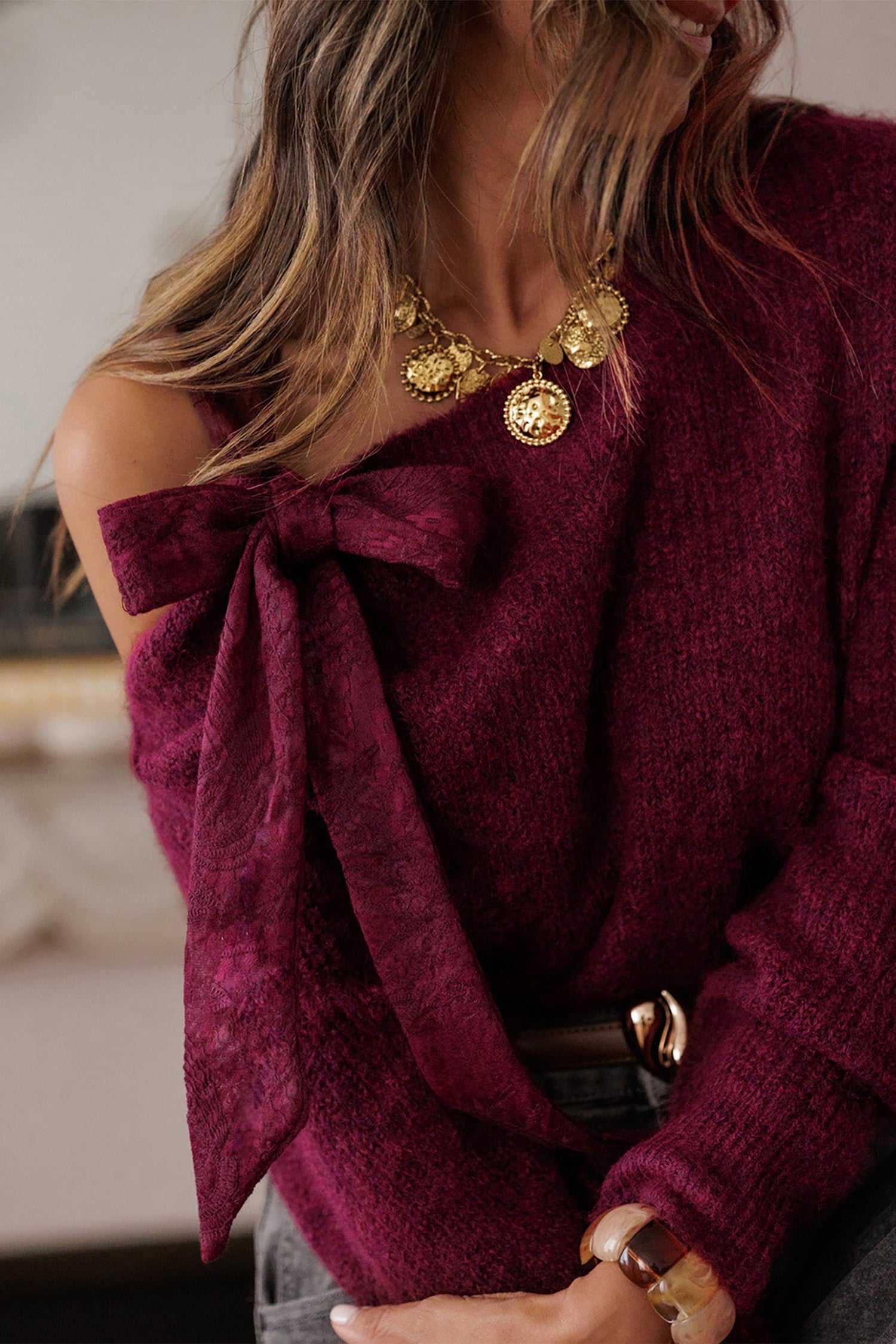 Stylish women's burgundy sweater with lace bow and asymmetric neckline. Cozy and elegant fall knitwear for fashionable seasonal outfits.