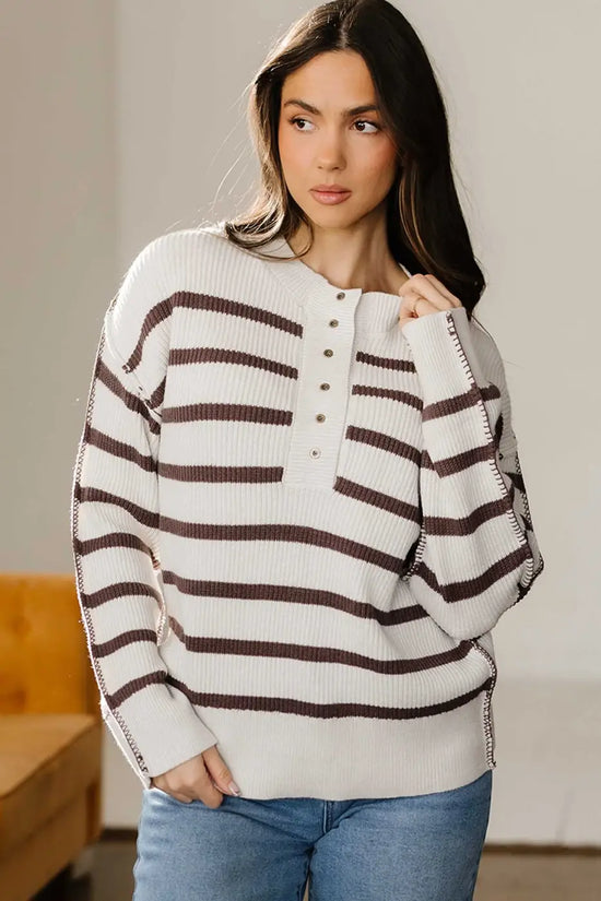 Cream and brown striped Henley jumper with ribbed knit and button front, styled casually with denim jeans.