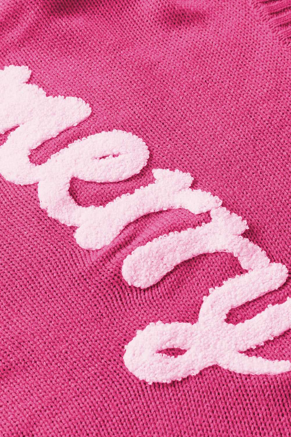 Close-up of white 'merry' embroidery on pink sweater, highlighting festive design for Christmas fashion.
