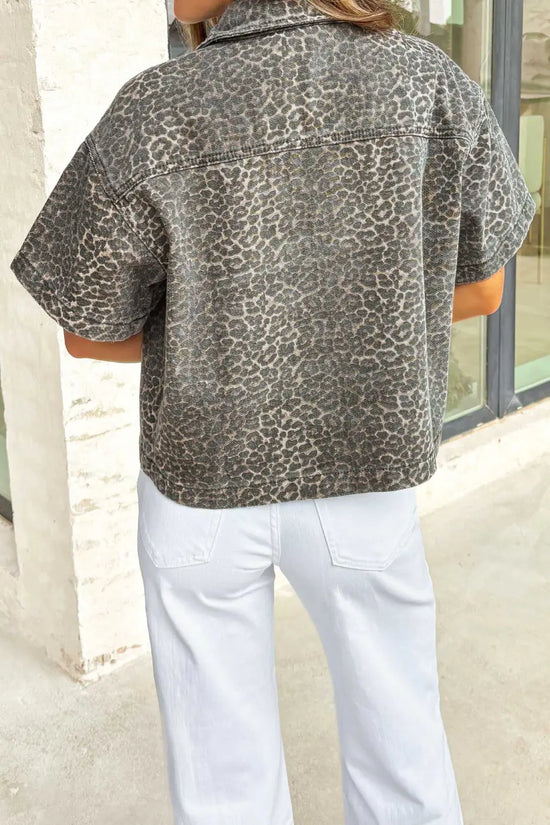 Back view of women's gray leopard short sleeve denim shirt featuring all-over leopard print and cropped western style.