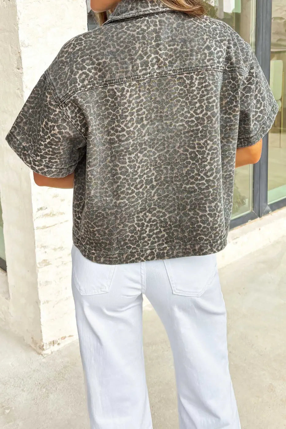 Back view of women's gray leopard short sleeve denim shirt featuring all-over leopard print and cropped western style.