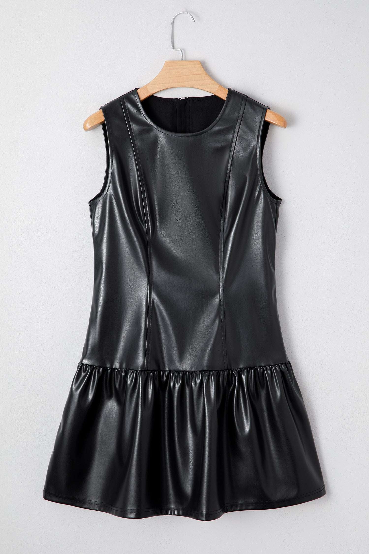 Ladies Black Faux Leather Mini Dress | FashionFitz displayed on hanger showing structured bodice and ruffled mini skirt design.