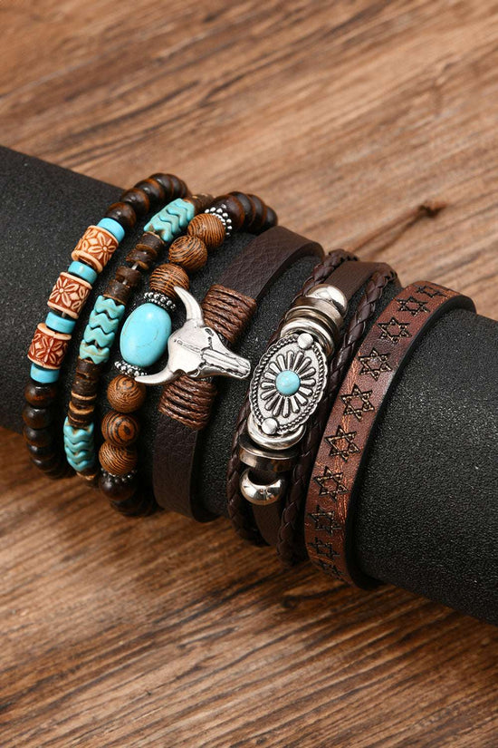 Stack of Western Bull Skull Turquoise Bracelets on a wrist against a wooden background