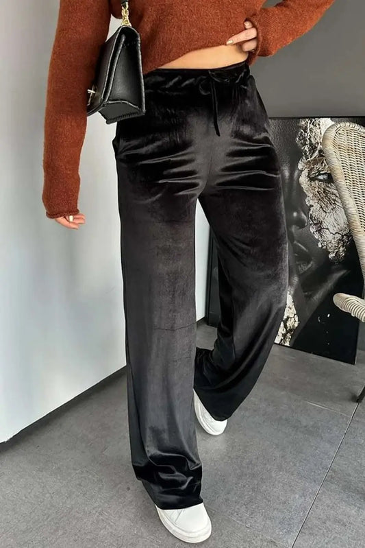 Black velvet straight-leg trousers with drawstring waist styled with a rust sweater and white sneakers. Elegant women’s pants for casual wear.