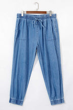 Flat lay of Plus Size Blue Denim Joggers with drawstring waist and front patch pockets, made from soft denim for everyday comfort.