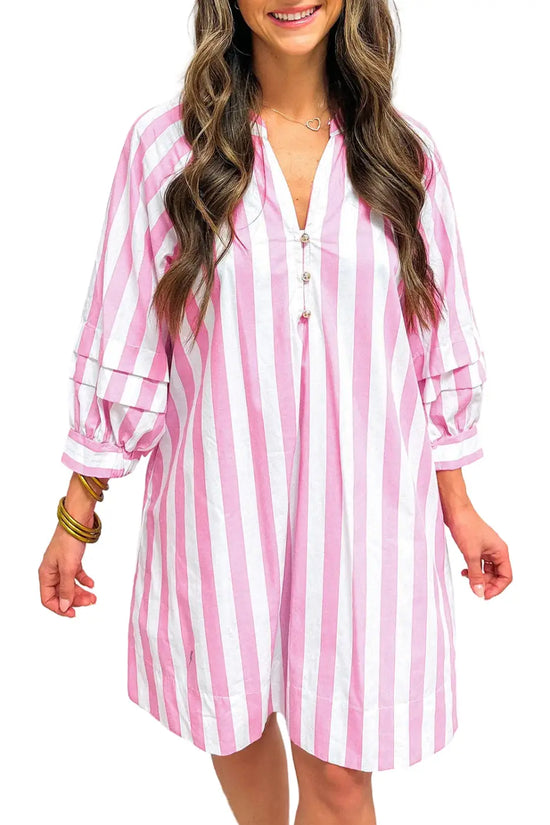Woman wearing a pink and white striped dress against a plain background