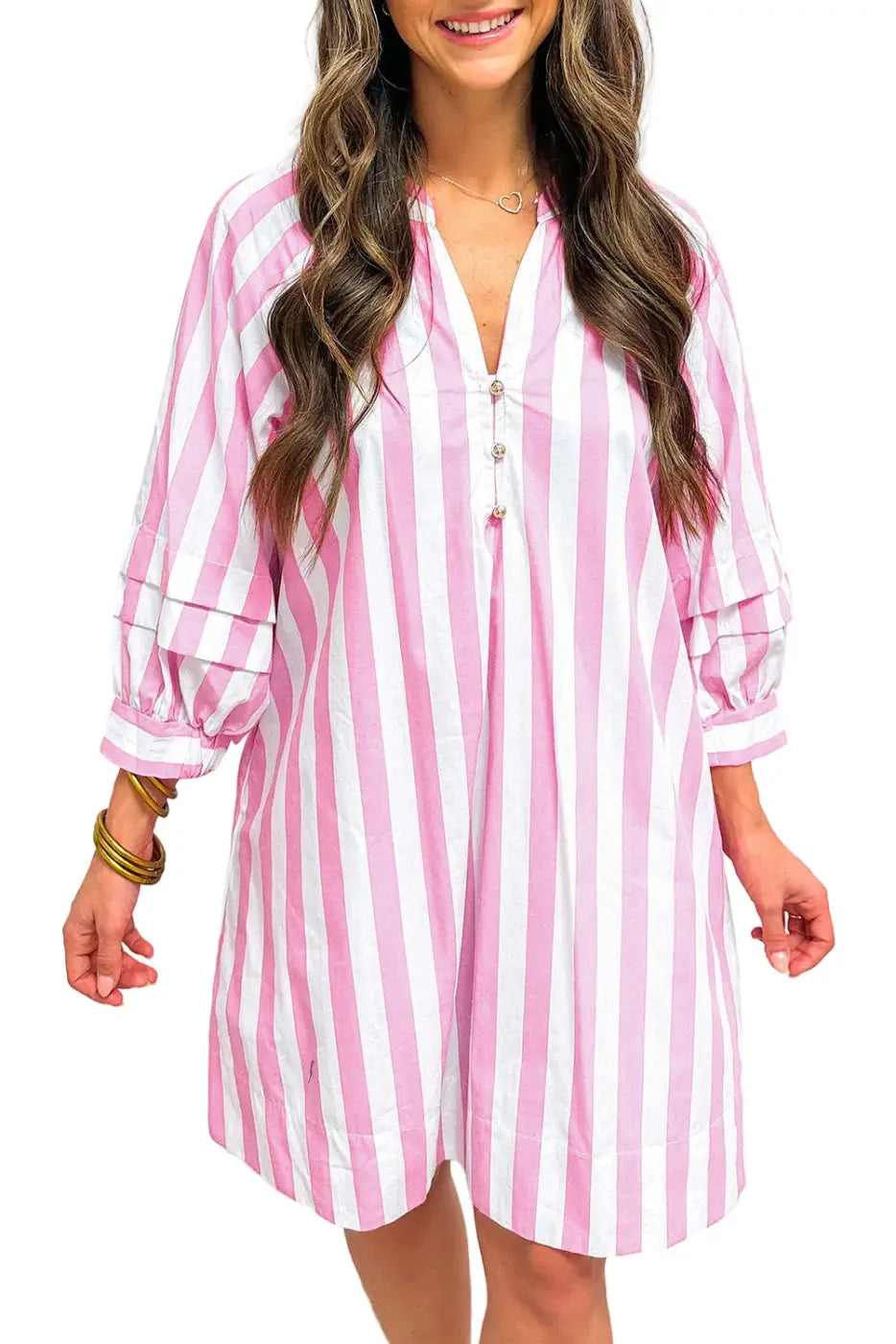 Woman wearing a pink and white striped dress against a plain background