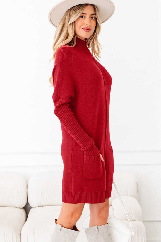 Side profile of red high neck knit jumper dress with ribbed sleeves and patch pockets. Soft knit fabric perfect for winter styling.