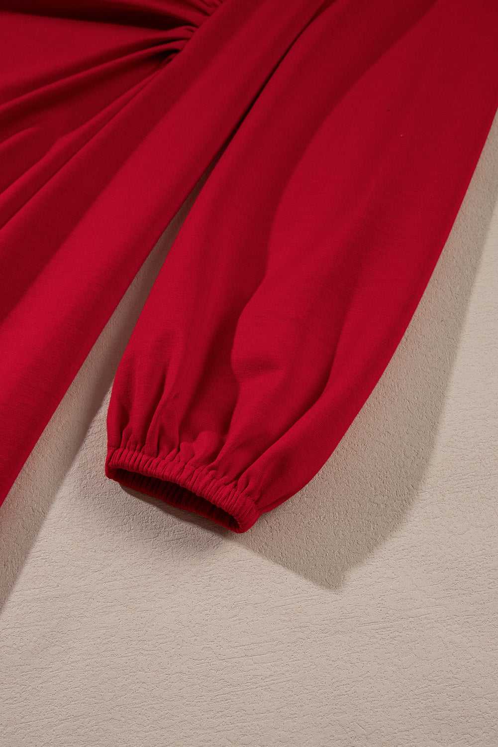 Detailed view of the elastic cuff on the Red Long Sleeve Drape Midi Dress, showcasing comfort and style for autumn fashion.