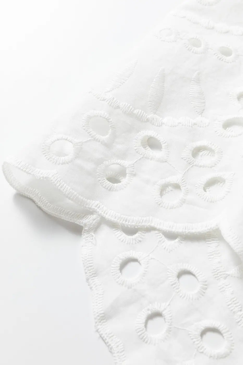 Scalloped hem detail of White Cutwork Embroidered Crop Top, featuring delicate embroidery and breathable cotton fabric.