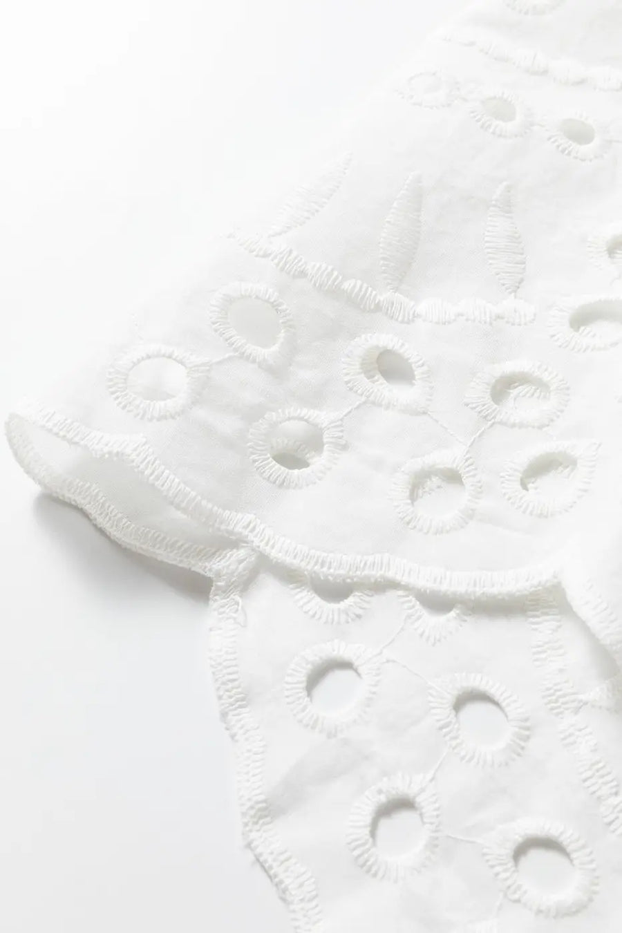 Scalloped hem detail of White Cutwork Embroidered Crop Top, featuring delicate embroidery and breathable cotton fabric.