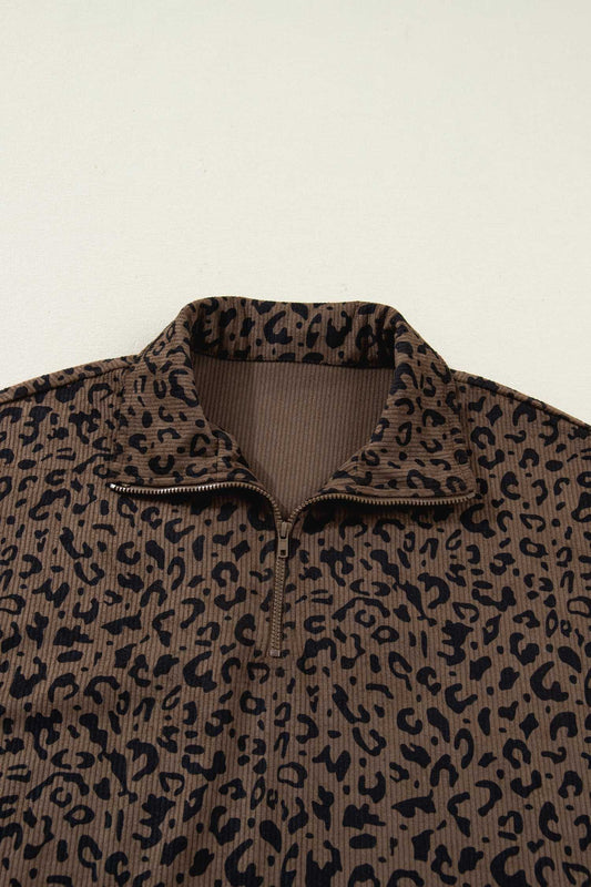 Close-up of brown leopard print corduroy half-zip jumper collar. Features ribbed inner lining and bold animal print pattern.