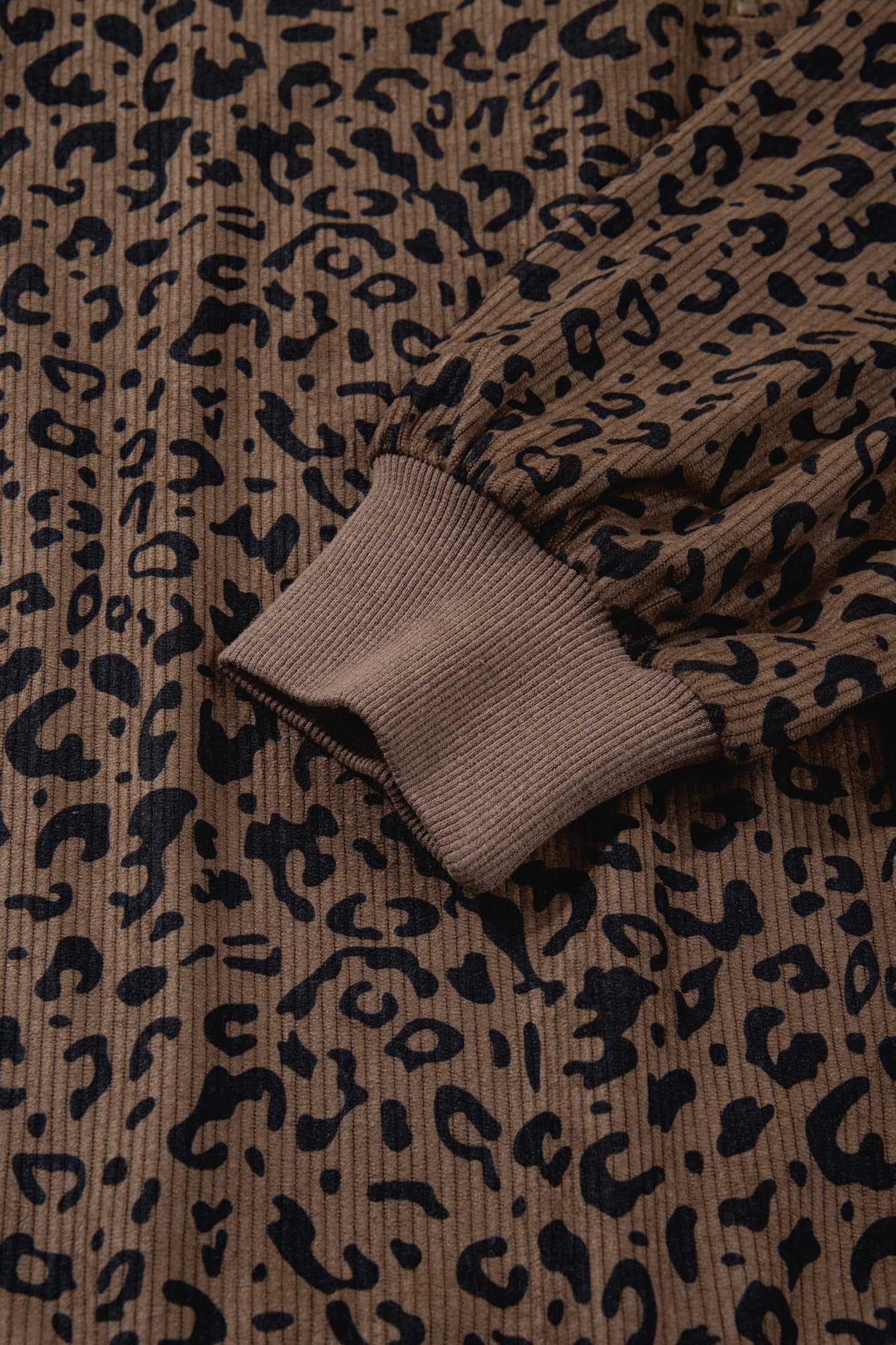 Sleeve and cuff detail of brown leopard print corduroy half-zip jumper. Ribbed cuff adds comfort and style to this fall essential.